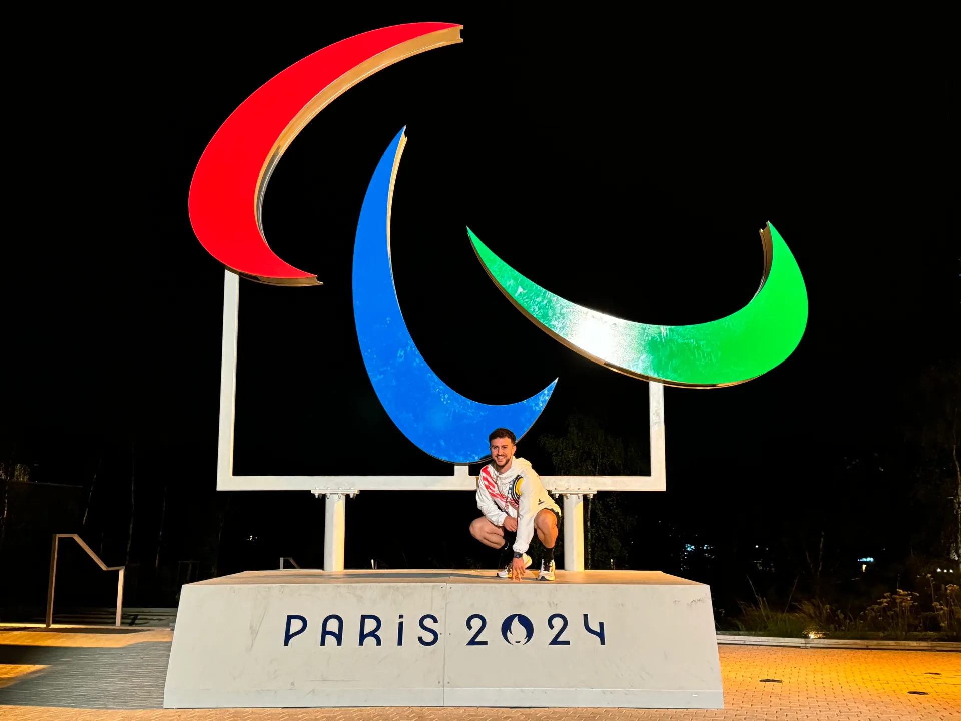 Maxime Barbarotto devant le symbole paralympique de Paris 2024, de nuit